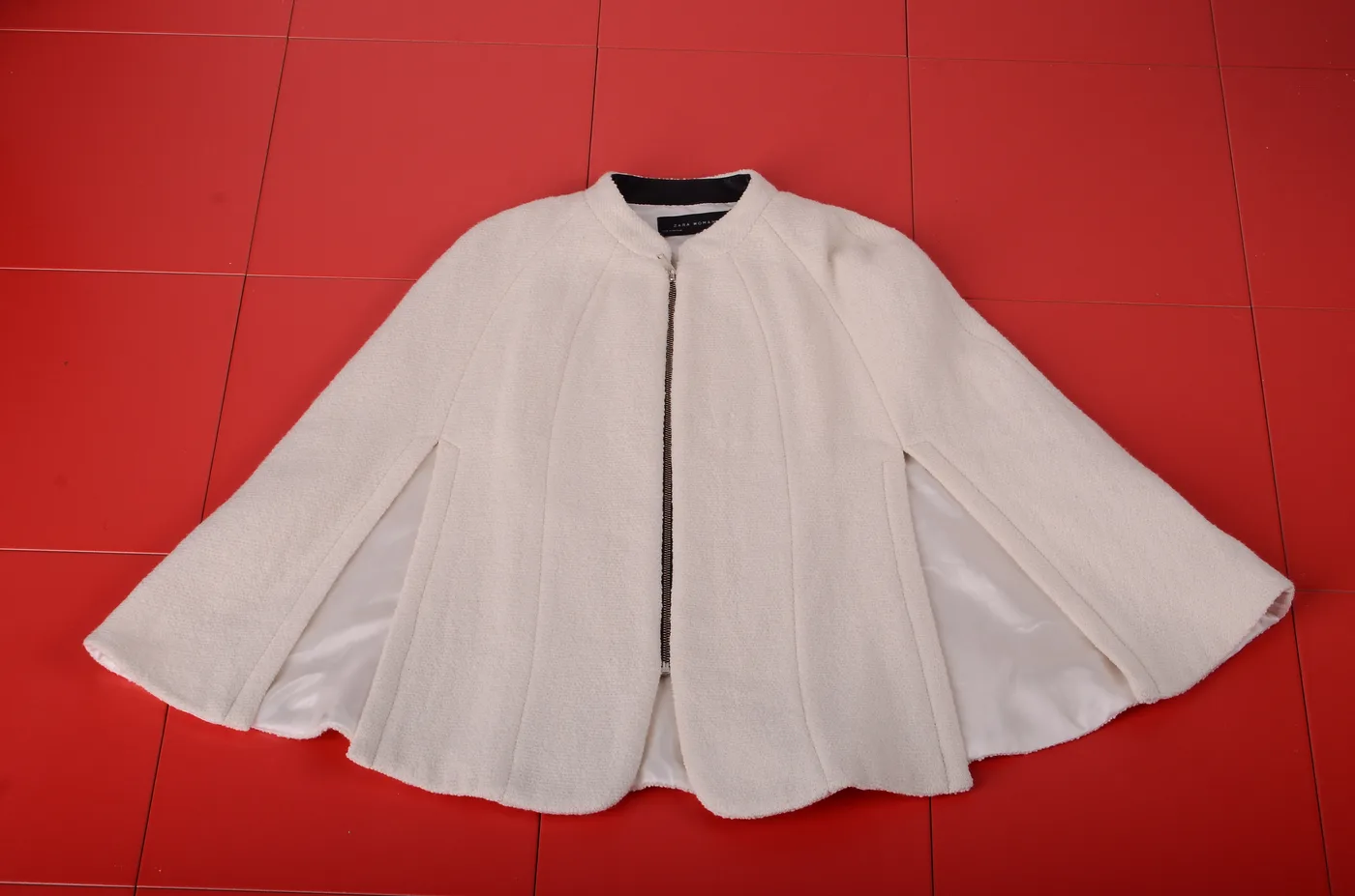 Cream cape jacket photographed on a red floor, Outfitters Winter 2016